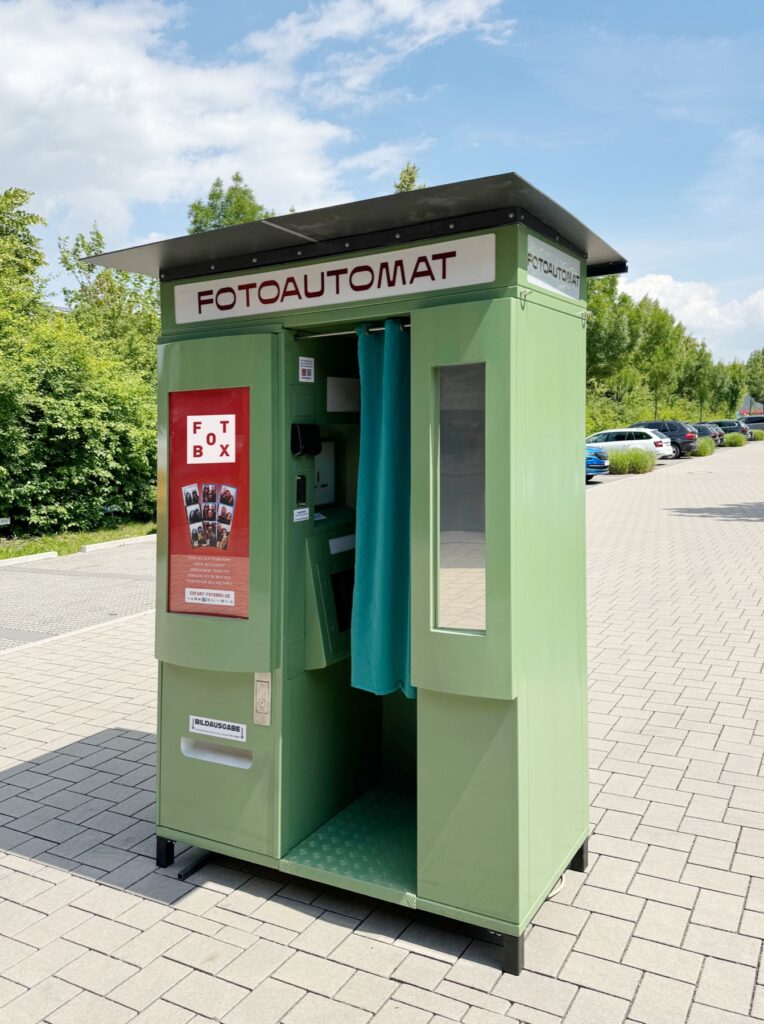 Grüner Fotoautomat mit Dach und Leuchtschild